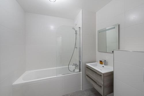 Un baño blanco con ducha y lavabo. en Perle De Savoie - Apt B303 - BO Immobilier - remises sur les forfaits de skis Châtel ou Portes du soleil, en Châtel
