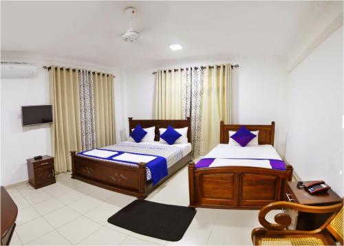 a bedroom with two beds and a desk and a tv at Ronaka Airport Transit Hotel in Katunayake