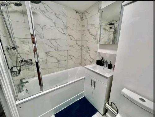 a bathroom with a shower and a tub and a sink at Lovely 2BR Suite in Bow, E3 in London