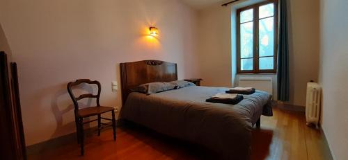 ein Schlafzimmer mit einem Bett, einem Stuhl und einem Fenster in der Unterkunft Bienvenue chez Fanny in Bussières