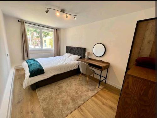 a bedroom with a bed and a desk with a mirror at Lovely 2BR Suite in Bow, E3 in London