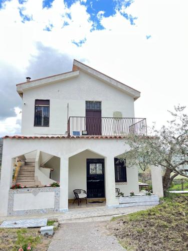 a white house with a balcony on top of it at Villetta con Oliveto CFG in Prizzi