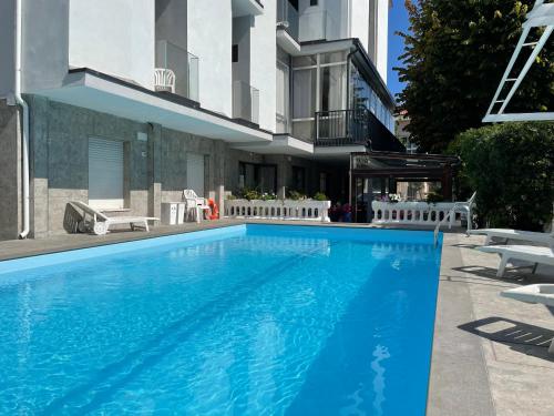 a large blue swimming pool in front of a building at Hotel Apis in Rimini