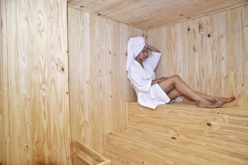una mujer está sentada en una sauna de madera en Las Orquídeas Hotel Boutique, en Asunción