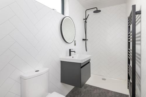 a white bathroom with a sink and a mirror at Oak Tree, Penruddock in Penruddock