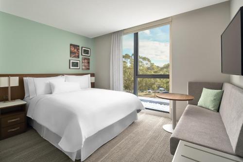 a bedroom with a large white bed and a couch at Element Melbourne Richmond in Melbourne
