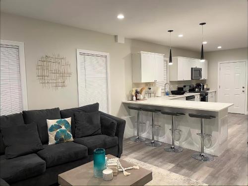 a living room with a black couch and a kitchen at Cozy Short & Suite 4-Bedroom Stay- Minutes to City in Quincy