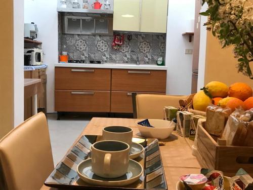 una cocina con una mesa con tazas y un bol de fruta en B&B CASA ELISABETTA, en Ginosa