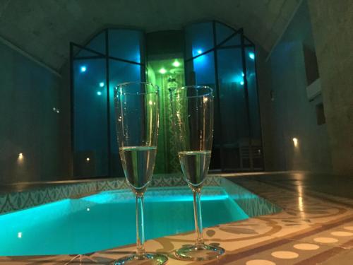 three wine glasses sitting next to a swimming pool at Palazzo Muro Leccese Relais de Charme & Wellness in Muro Leccese
