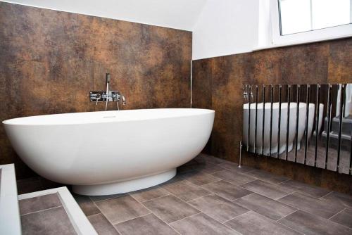 een badkamer met een groot wit bad in een kamer bij River Cottage, Keswick in Keswick