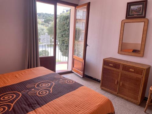 Schlafzimmer mit einem Bett, einem Spiegel und einem Fenster in der Unterkunft Apartamentos El Sol in Tossa de Mar
