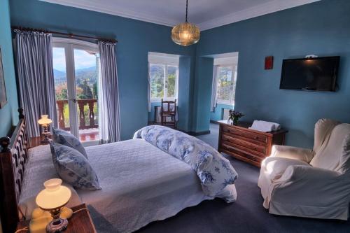 Gran Hotel La Cumbre في لا كومبر: غرفة نوم بجدران زرقاء وسرير وتلفزيون
