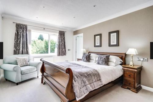 a bedroom with a bed and a chair and a window at Roxby, Pooley Bridge in Pooley Bridge