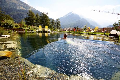 a man swimming in a body of water at Alpengasthof Grüner in Sölden