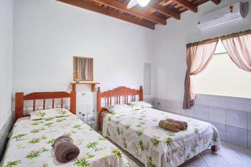 2 camas en una habitación con paredes y ventanas blancas en Casa Magnólia, en Paraty