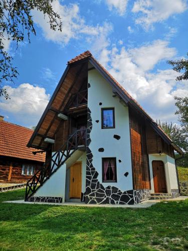 a small house with a gambrel roof with a rock at Konaci Gradina in Bajina Bašta