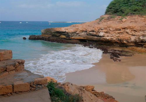 a beach with rocks and the water and the ocean at Villa Atum. Stella Maris Exclusive in Vila do Maio