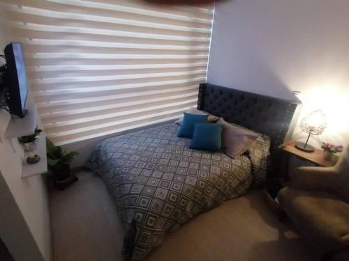 Dormitorio pequeño con cama con almohadas azules en Moderno Apartamento Chapinero Bogota, en Bogotá