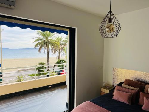 a bedroom with a bed and a view of the beach at T2 Front de Mer 2pers 1 minute de la plageT2 de 44 m2 plus terrasse 16m2 , vue mer panoramique et en face de la plage Cet appartement refait à neuf bénéficie d'un confort et d un équipement optima Cet appartement est idéal pour 2 personnes avec sa chamb in Le Lavandou