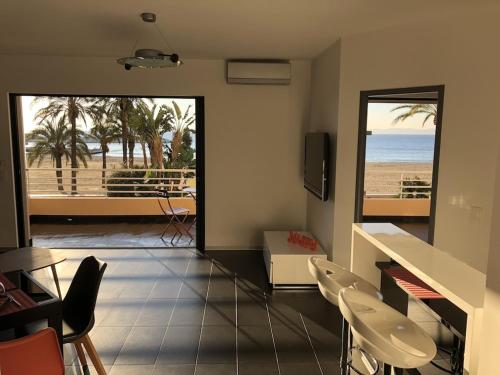 a living room with a view of the beach at T2 Front de Mer 2pers 1 minute de la plageT2 de 44 m2 plus terrasse 16m2 , vue mer panoramique et en face de la plage Cet appartement refait à neuf bénéficie d'un confort et d un équipement optima Cet appartement est idéal pour 2 personnes avec sa chamb in Le Lavandou