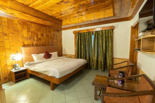 a bedroom with a bed and a wooden ceiling at Vivaan Stays -Holiday Home International in Manāli