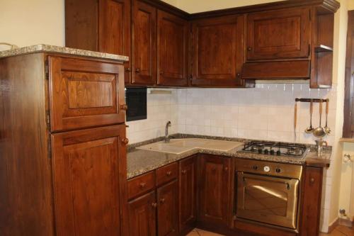 a kitchen with wooden cabinets and a stove top oven at affittacamere la torre in Tegoleto