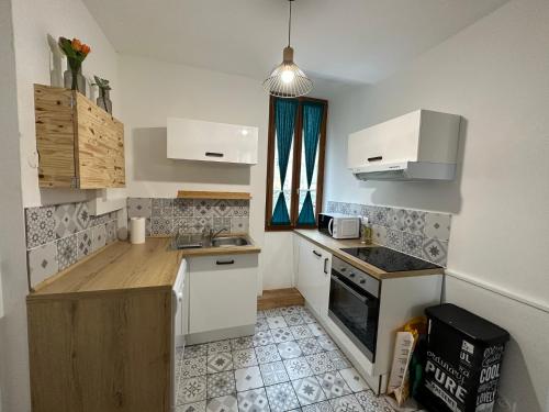 eine kleine Küche mit weißen Schränken und einem Herd in der Unterkunft Appartement spacieux - proche centre et therme in Bagnères-de-Bigorre