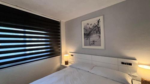 1 dormitorio con cama blanca y ventana en Apartamentos LOS TULIPANES en Salou