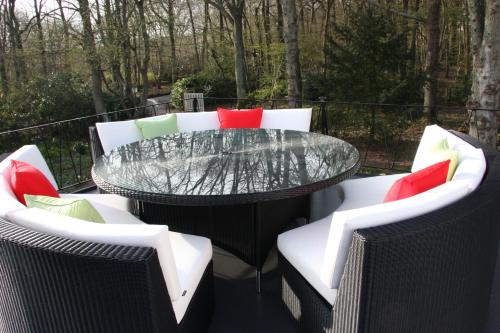 a patio with a glass table and chairs at White Lodge B&B in Cooksbridge