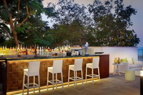 a bar with white stools in front of a counter at The St. Regis Saadiyat Island Resort, Abu Dhabi in Abu Dhabi