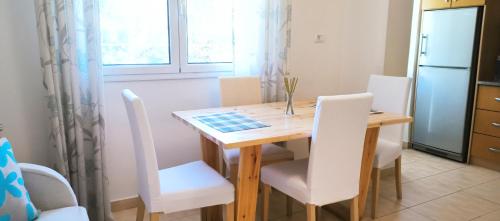 cocina con mesa de madera y sillas blancas en Central apartment, fully equipped, en Himare