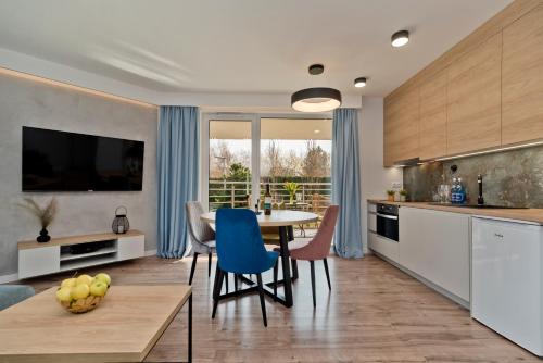 a kitchen and dining room with a table and blue chairs at BlueApart Apartamenty Na Klifie in Władysławowo