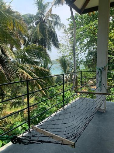 a hammock on a porch with a view of the ocean at Talalla Wonder View in Talalla South