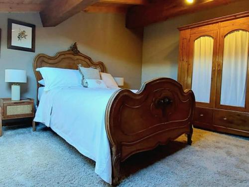 a bedroom with a large wooden bed with white sheets at Villa Segreta, Mount Etna in Belpasso