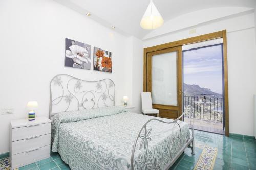 a white bedroom with a bed and a balcony at Via Col Vento in Ravello