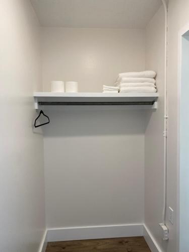 a white bathroom with white towels on a shelf at Innovative Studio Apartment in Gadsden