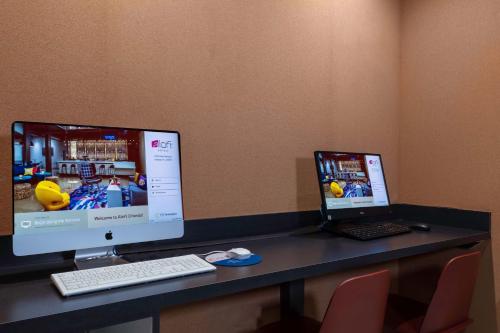 a desk with two monitors and a laptop on it at Aloft Orlando Lake Buena Vista in Orlando