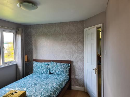 a bedroom with a bed with blue sheets and a window at The Reading whole chalet with lake and two acre gardens in Reading