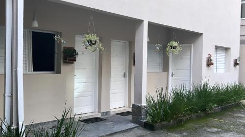a white house with two white doors and plants at Hotel Rio in Guarujá