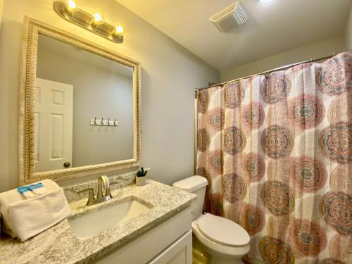 a bathroom with a sink and a toilet and a mirror at Sand Dollar 2 by ALBVR - Walking distance to Hangout! Beautifully redone condo! in Gulf Shores
