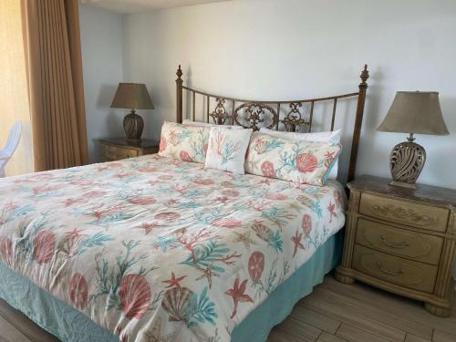 a bedroom with a bed with a floral bedspread and two night stands at Summer House 703B by ALBVR - Great Beachfront Condo with Oversized Balcony & Amazing Views! in Orange Beach