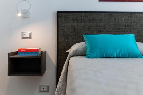 a bed with a blue pillow and a side table at Elegance Suite Apartments - Siroli Collection in Cervia