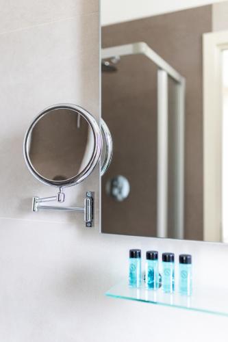 a bathroom sink with a mirror and some bottles on a shelf at Elegance Suite Apartments - Siroli Collection in Cervia