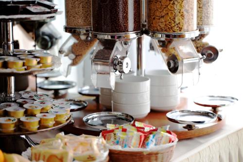 a counter with cupcakes and a coffee machine and a table with food at Hotel Dei Fiori in Milan