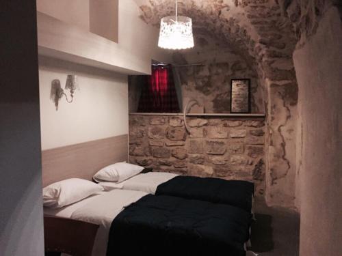 a bedroom with two beds and a stone wall at Al-Hakim Boutique Hotel Old Town Nazareth in Nazareth