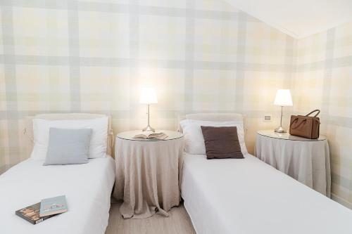 a room with two beds and two tables with lamps at Hotel Eden in Sistiana