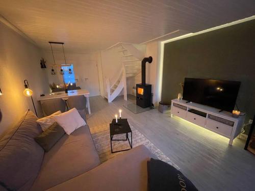 a living room with a couch and a flat screen tv at Nordseetraum - Ferienhaus Wolke in Friedrichskoog
