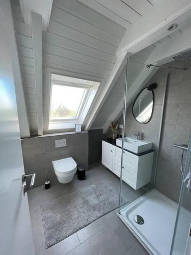 a bathroom with a toilet and a sink and a window at Nordseetraum - Ferienhaus Wolke in Friedrichskoog