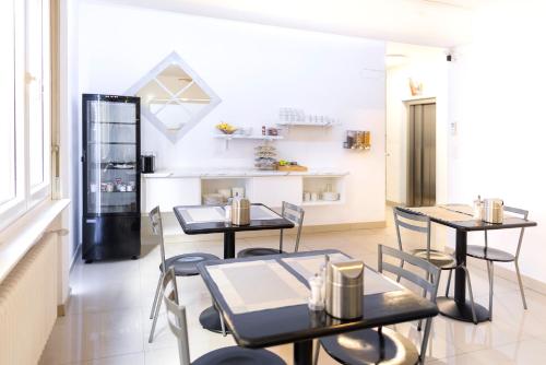 uma sala de jantar com mesas e cadeiras e um frigorífico em Hotel San Carlo em Lugano