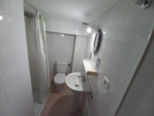 La salle de bains blanche est pourvue de toilettes et d'un lavabo. dans l'établissement El Laberinto, à Sotillo de la Adrada
